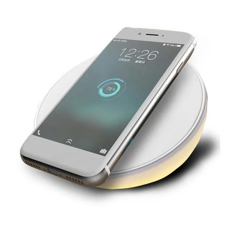 White wireless charger with digital clock display and night light feature on a bedside table
