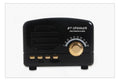 Compact vintage-style wood grain finish Bluetooth speaker on a wooden surface.