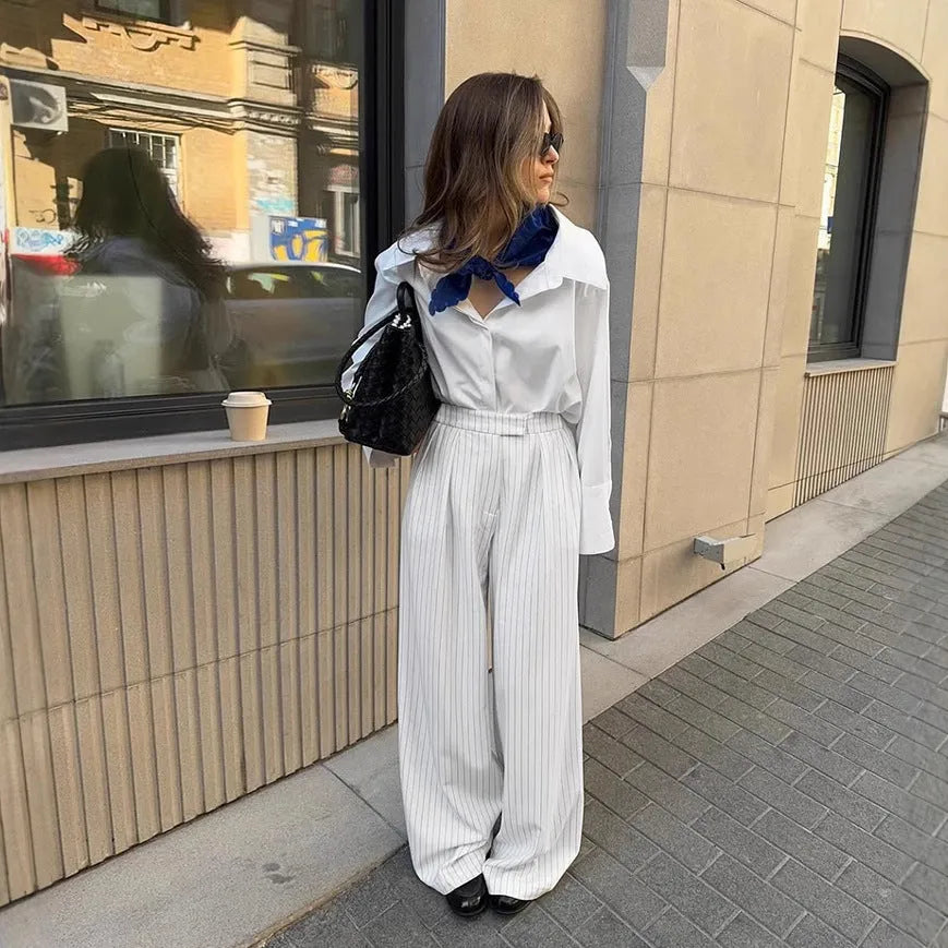 White striped wide-leg women's trousers with a front zipper on a hanger.