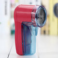 White portable electric lint remover for clothing, showing compact size and USB-C charging port.