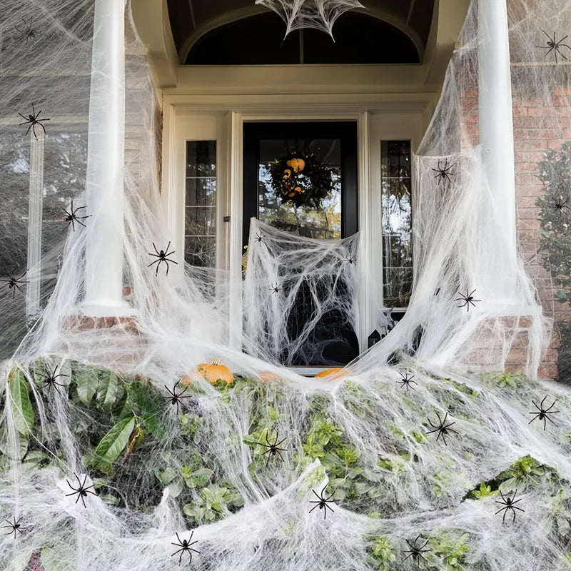 White cotton spider web Halloween decoration with multiple attached spiders draped over a surface.