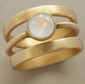 Geometric hollow gold-plated ring with micro-inlaid white chalcedony stones on a titanium steel band.