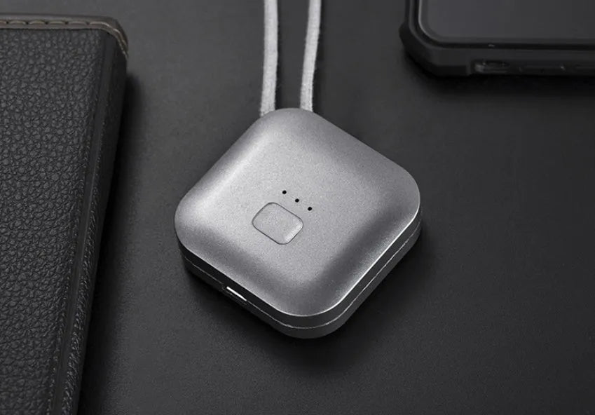 Small pink USB portable air purifier necklace on a table with charging cable.