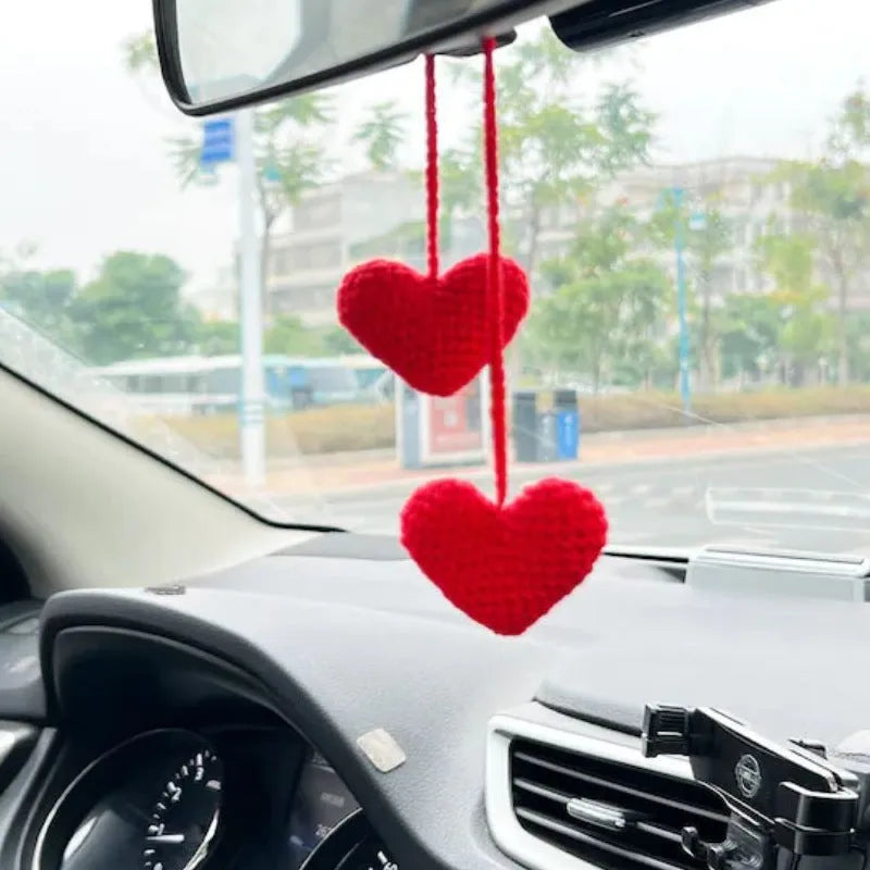 Green and white knitted wool car plant decoration with hanging rope on a car dashboard