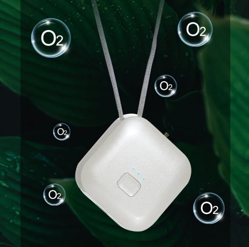 Small pink USB portable air purifier necklace on a table with charging cable.