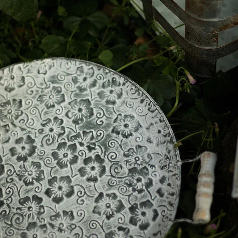 Round wrought iron storage tray in a classic metal colour on a wooden surface.