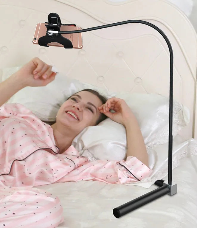 Black bedside phone holder with universal mobile phone bracket and adjustable overhead support shelf positioned next to bed