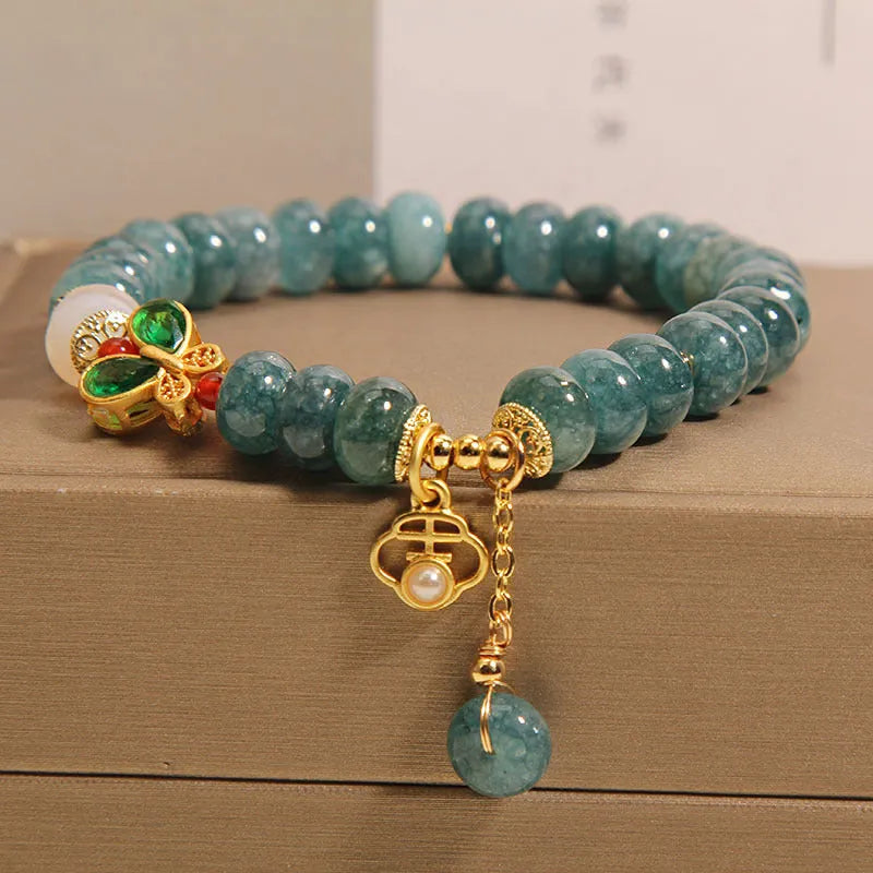 Blue water jade abacus bead bracelet with butterfly charm and white agate on an alloy band.