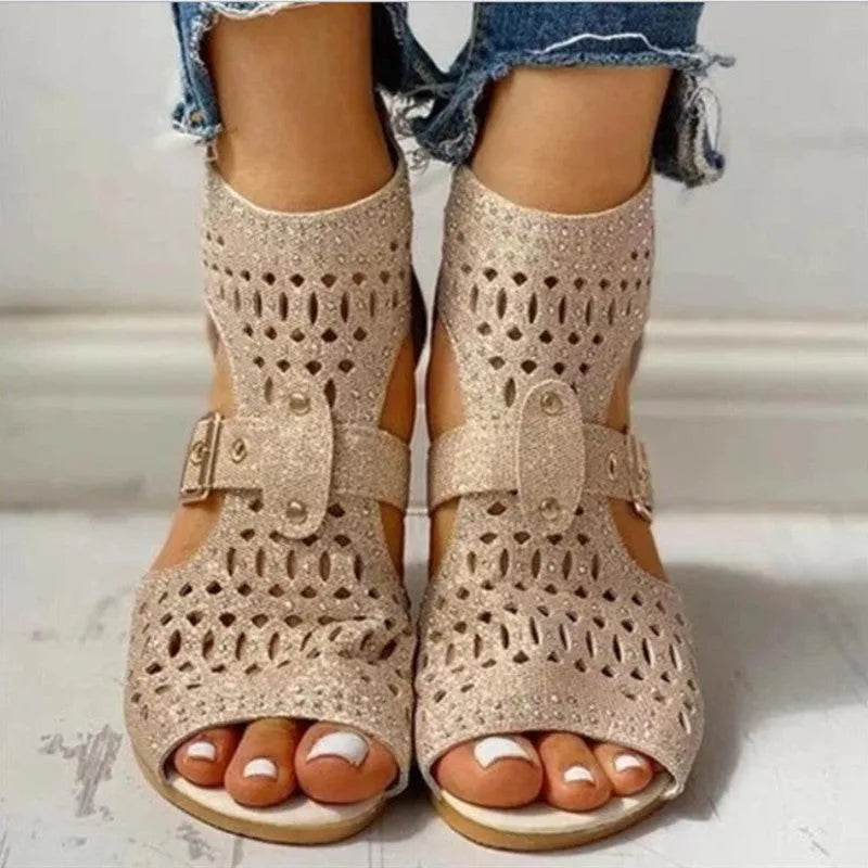 Women's beige flat sandals with back zipper and low wedge heel on a white background.