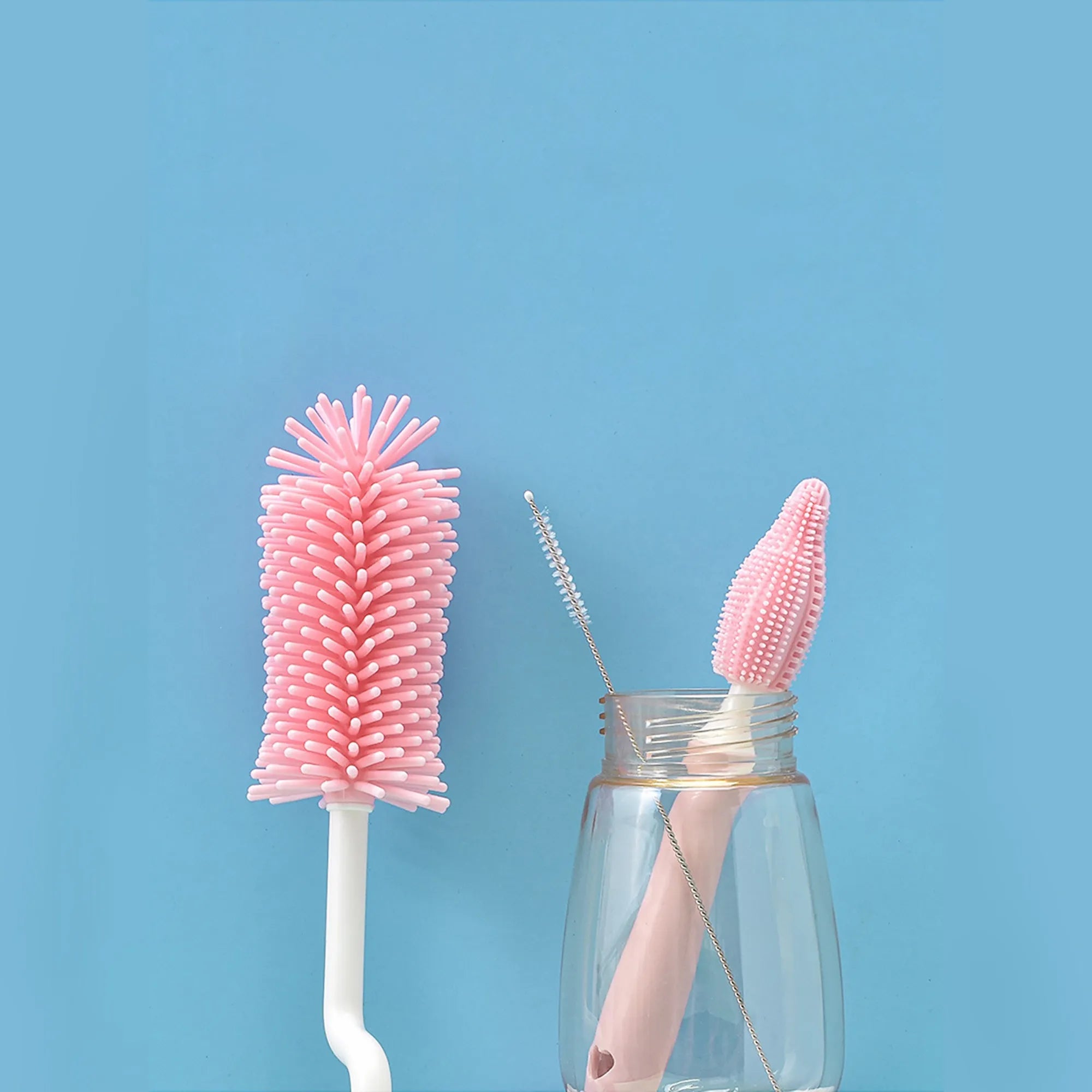 Three-piece baby bottle cleaning brush set with silicone bristles and a straw cleaner in assorted colours.