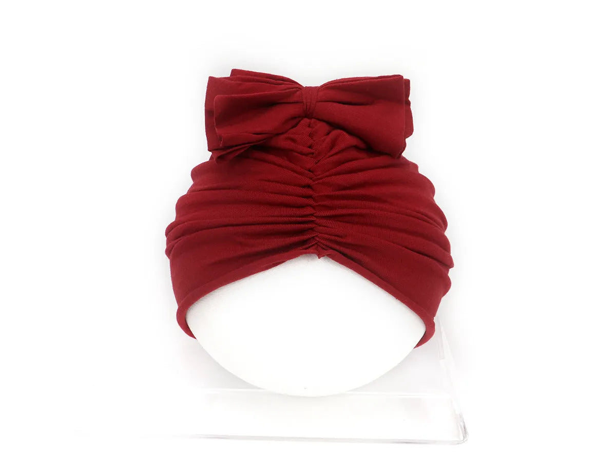Soft knitted acrylic baby turban hat in a solid colour, shown on a mannequin.