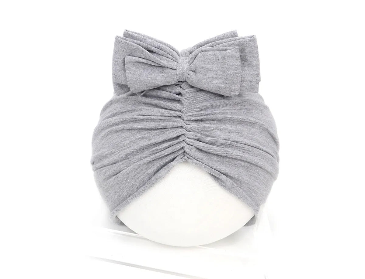 Soft knitted acrylic baby turban hat in a solid colour, shown on a mannequin.