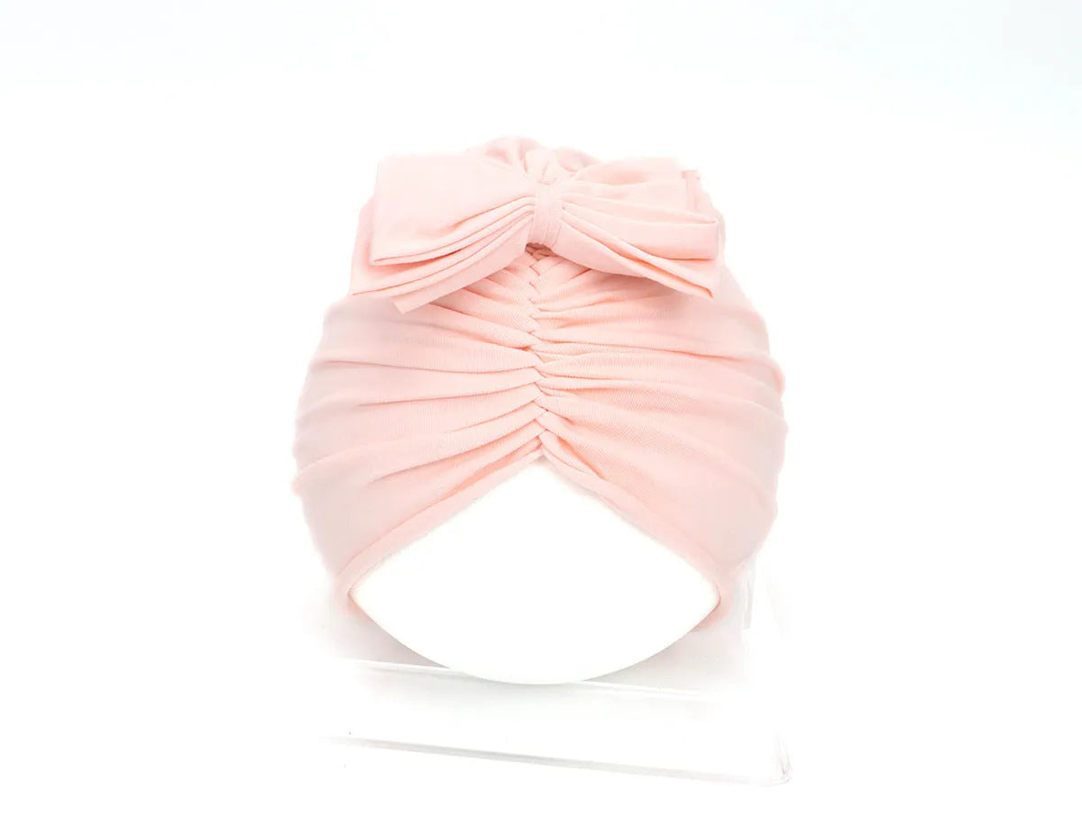 Soft knitted acrylic baby turban hat in a solid colour, shown on a mannequin.