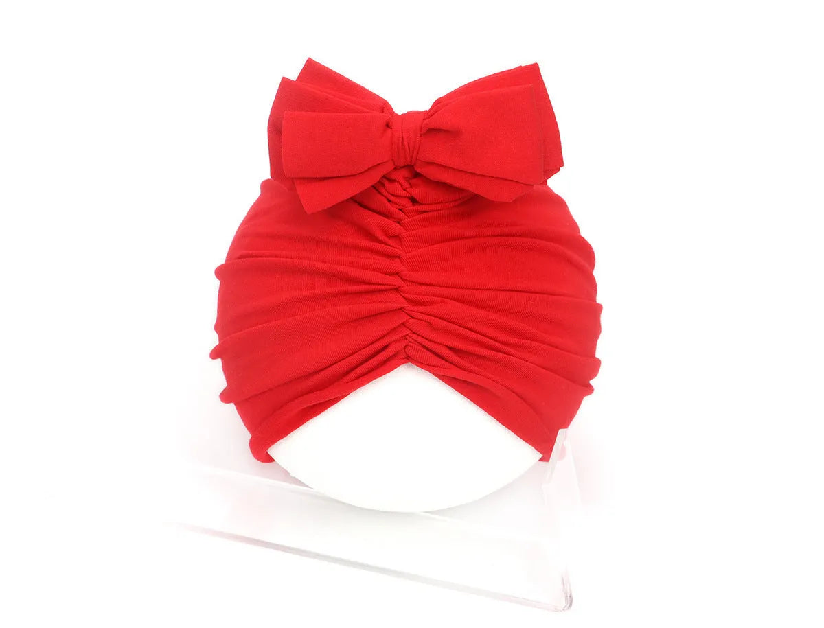 Soft knitted acrylic baby turban hat in a solid colour, shown on a mannequin.