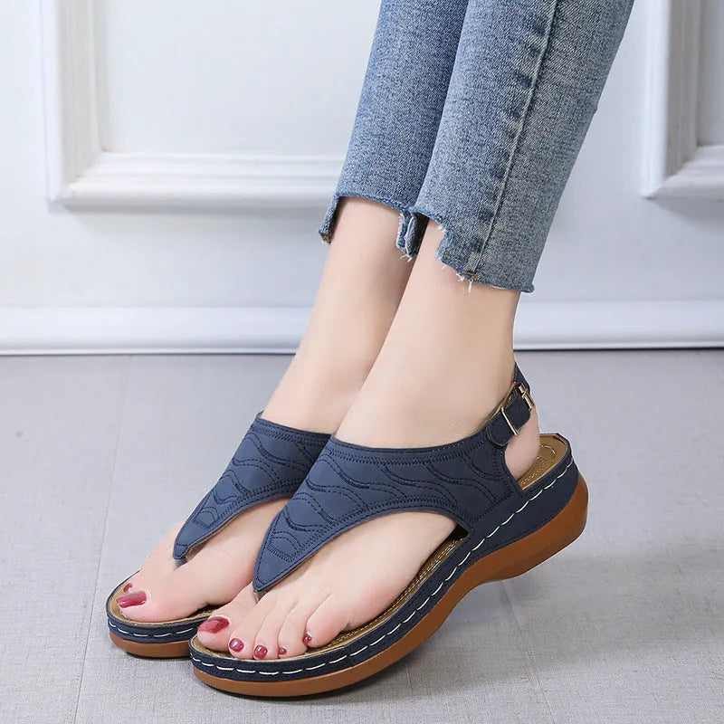 Women's wedge heel flip flop sandals with an adjustable buckle back strap in black.