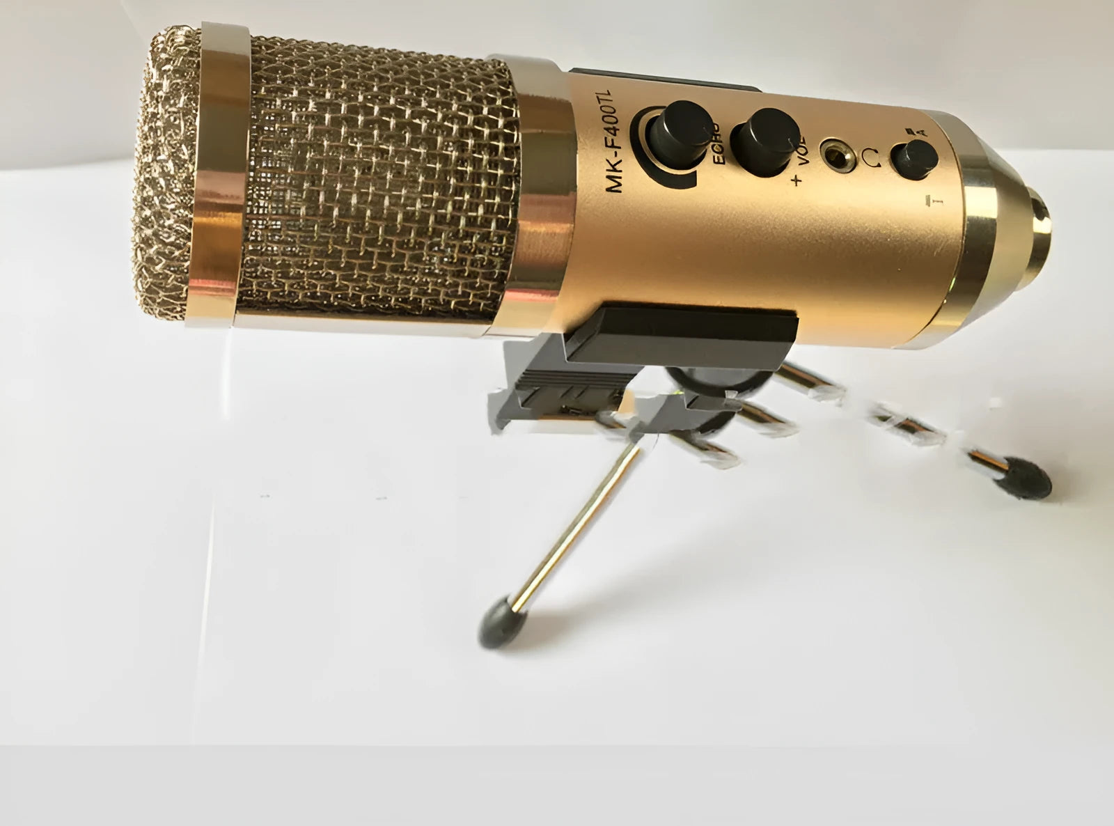 Gold wireless condenser microphone with built-in stand on a desk