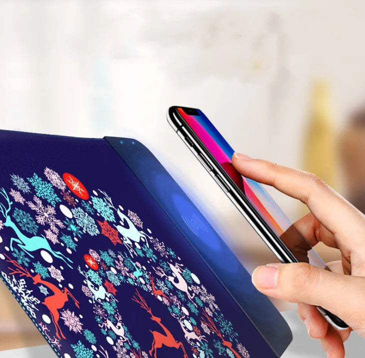 Black wireless charging mouse pad with RGB edge lighting and a white cartoon dot pattern on a desk.