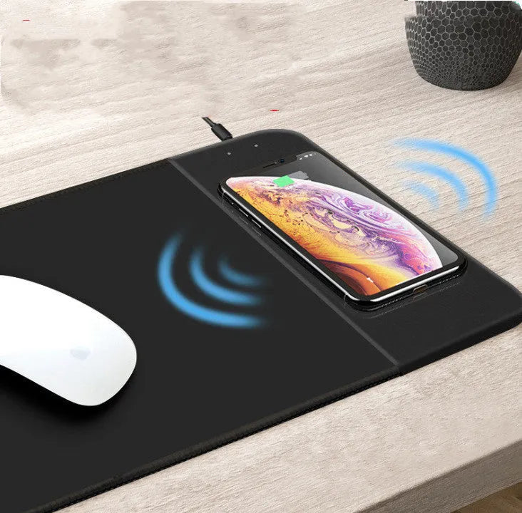 Black wireless charging mouse pad with RGB edge lighting and a white cartoon dot pattern on a desk.