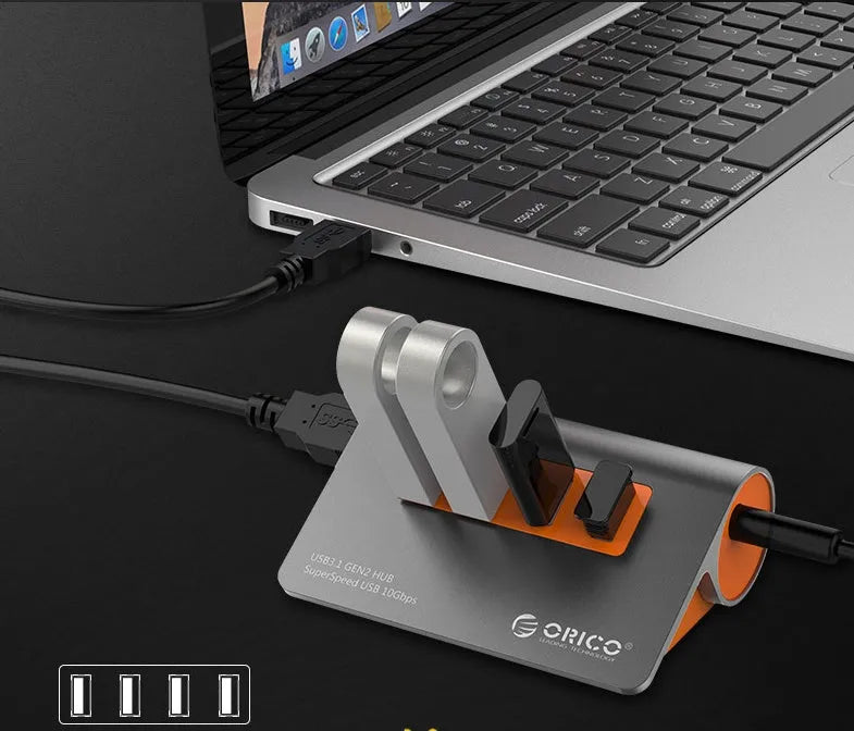 Dark grey aluminium USB-C docking station with four USB ports and orange accent, shown with a detached cable.