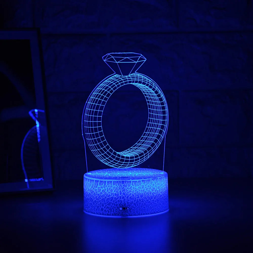 3D diamond ring LED night light with colour-changing illumination on a black base.
