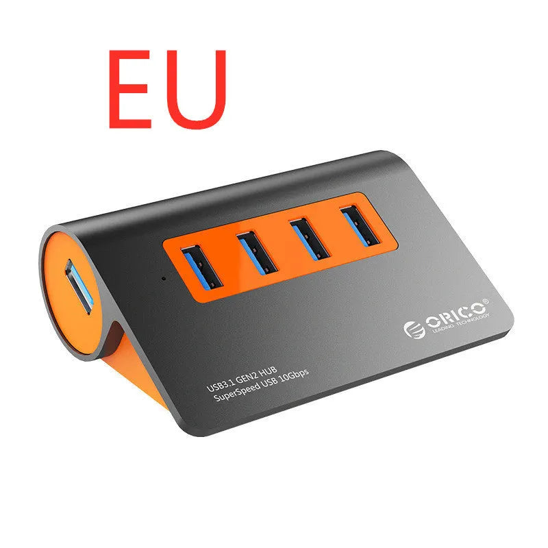 Dark grey aluminium USB-C docking station with four USB ports and orange accent, shown with a detached cable.