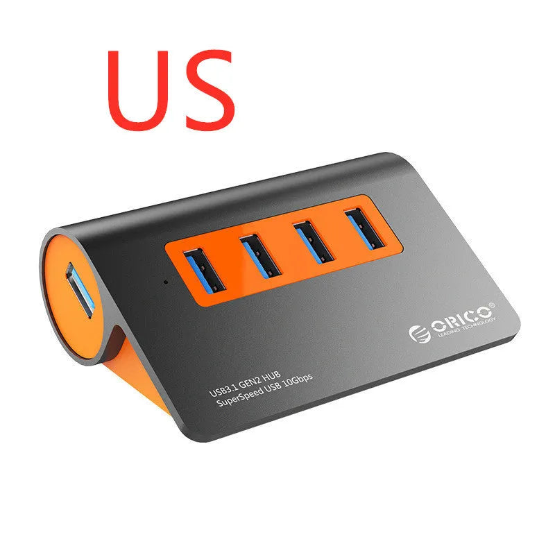 Dark grey aluminium USB-C docking station with four USB ports and orange accent, shown with a detached cable.