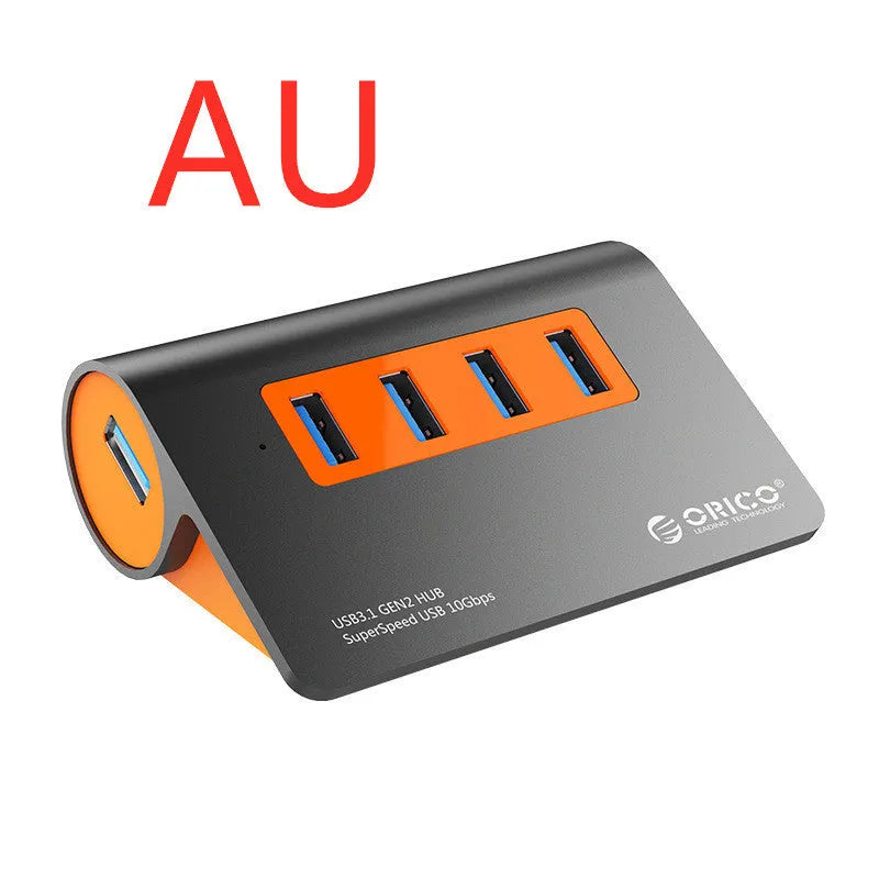 Dark grey aluminium USB-C docking station with four USB ports and orange accent, shown with a detached cable.