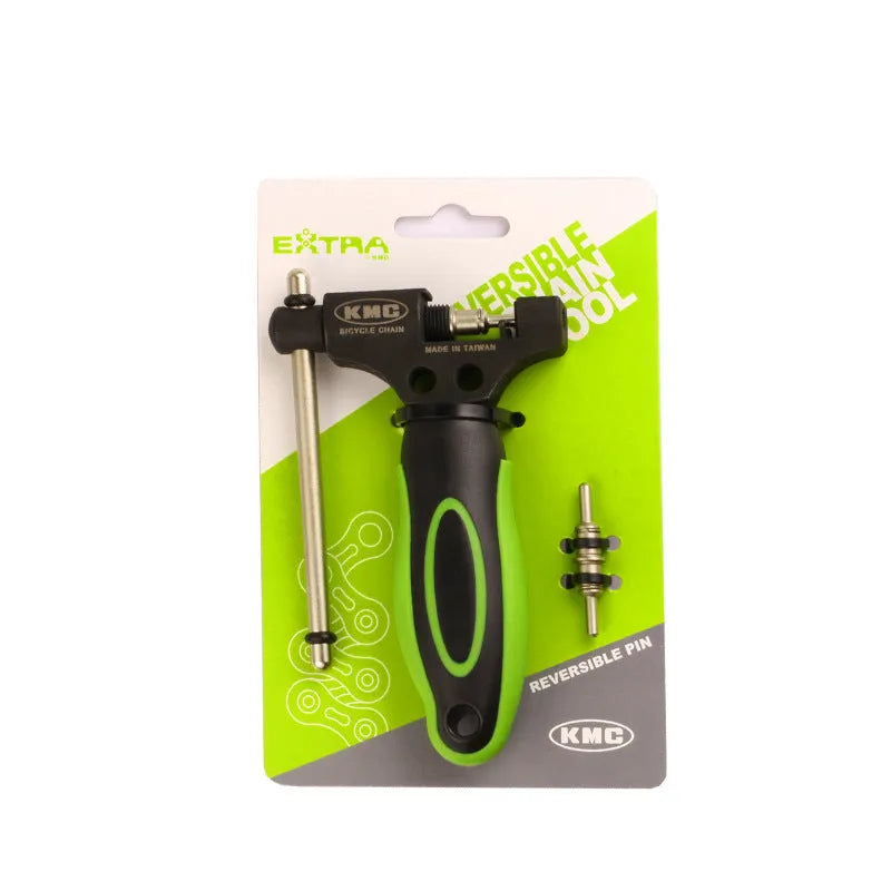 A green steel bicycle chain next to a double shaft chain cutting tool on a workshop surface.