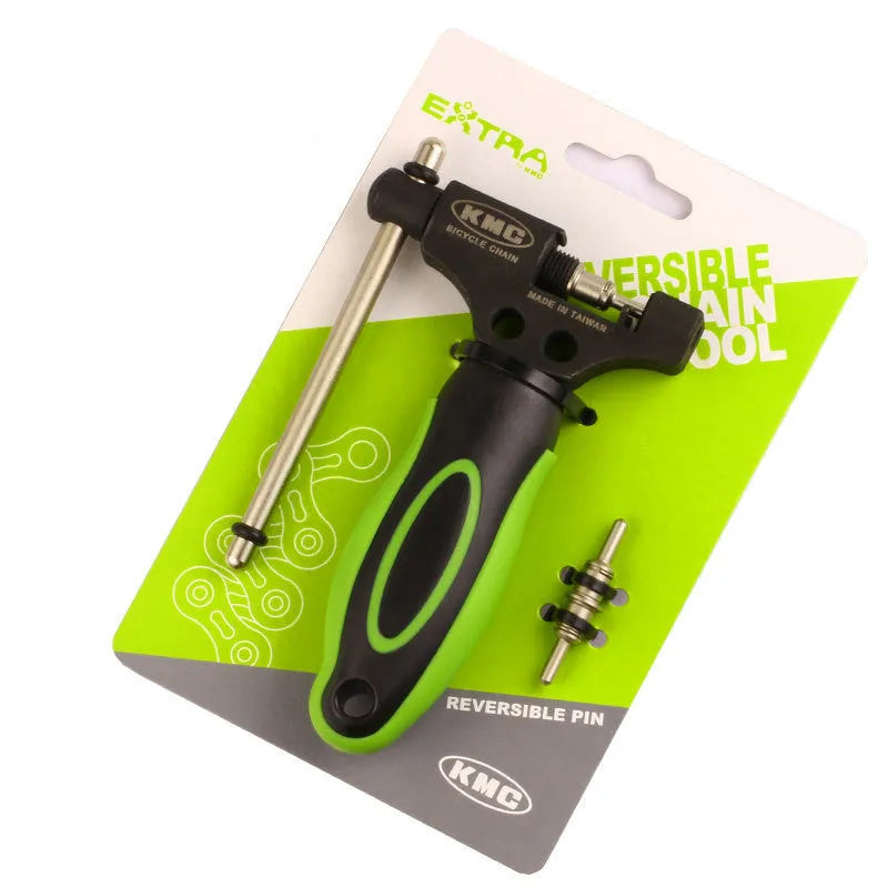 A green steel bicycle chain next to a double shaft chain cutting tool on a workshop surface.