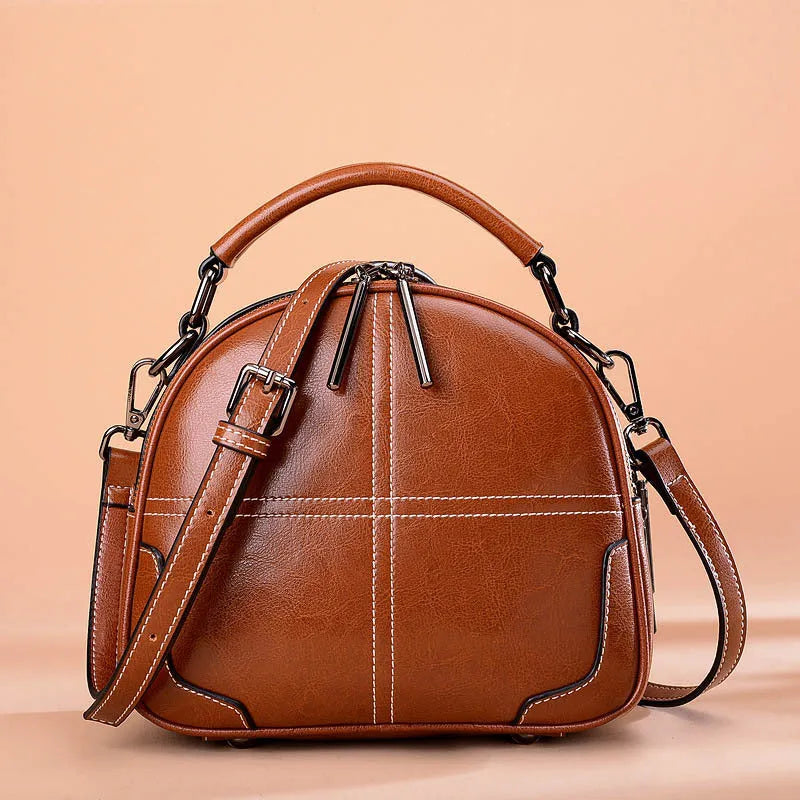Round leather handbag in wine red with zipper and soft handles showing 21cm dimensions