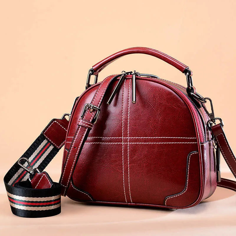 Round leather handbag in wine red with zipper and soft handles showing 21cm dimensions