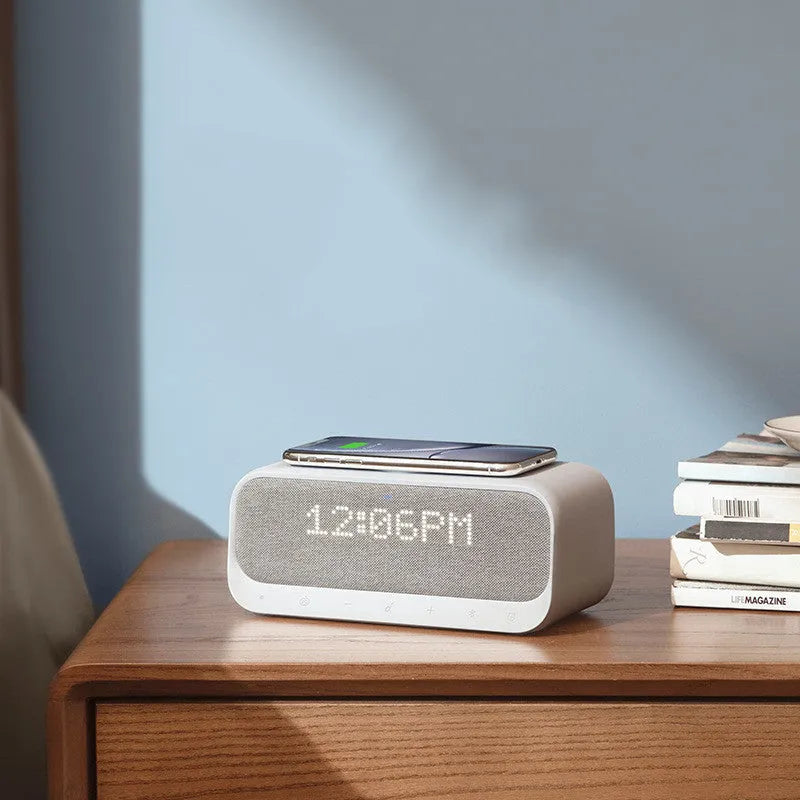 Soundcore white Bluetooth speaker with wireless charging pad and digital display showing alarm clock