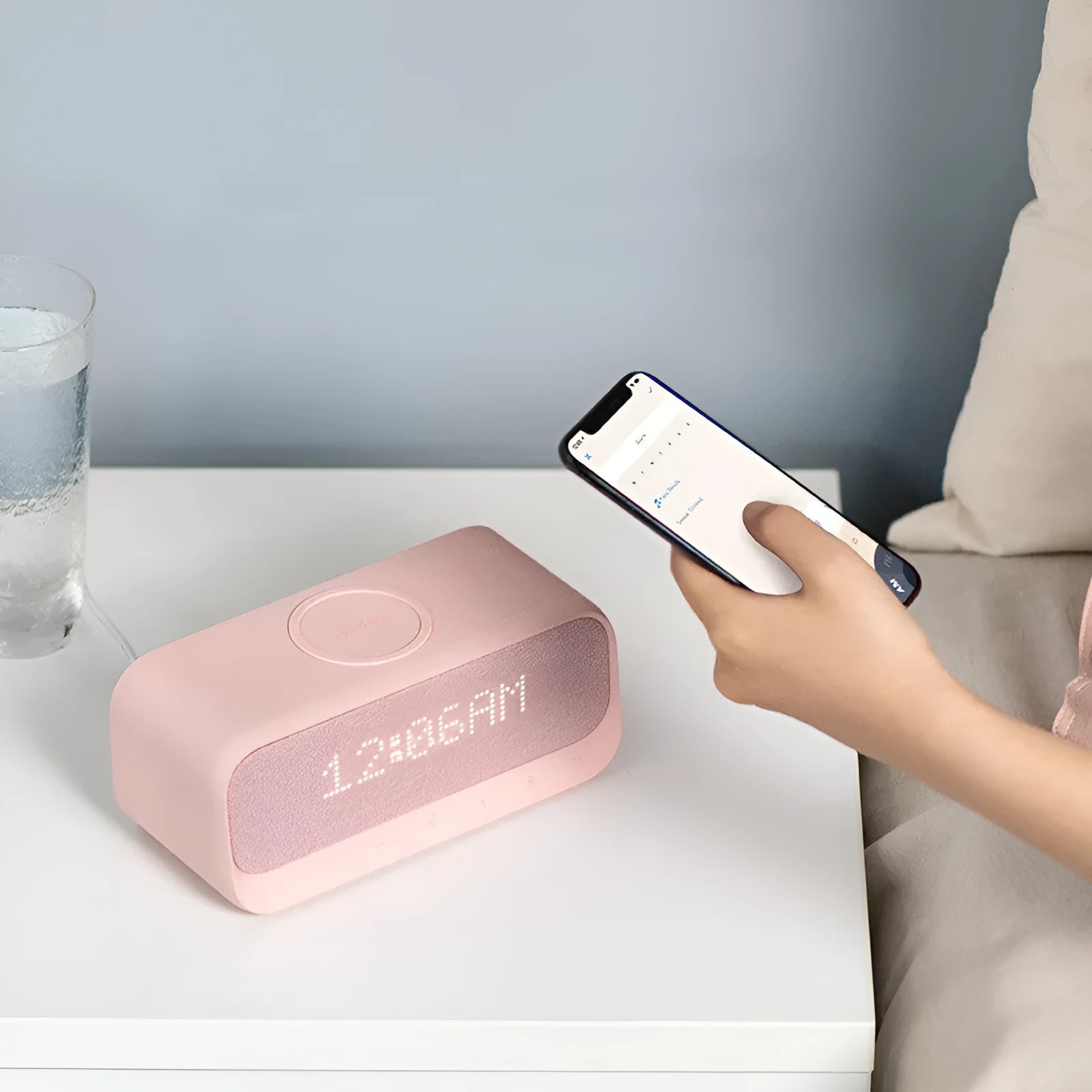 Soundcore white Bluetooth speaker with wireless charging pad and digital display showing alarm clock