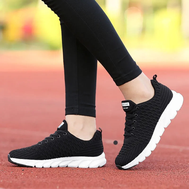 Women's running shoes in black, pink, or white with a breathable fly weave upper and wear-resistant outsole.
