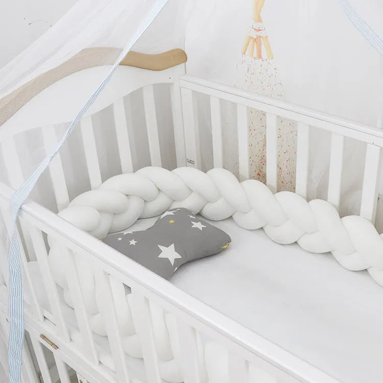 Bendable braid-knot baby crib bumper in spandex velvet, shown in a light grey colour wrapped around a cot.