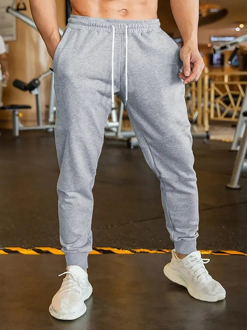 Men's loose-fit casual trousers with an elastic drawstring waist in a neutral colour.
