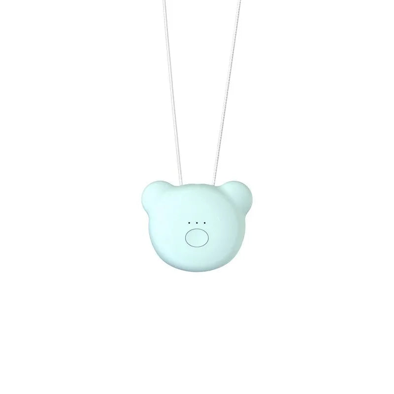 Small pink USB portable air purifier necklace on a table with charging cable.