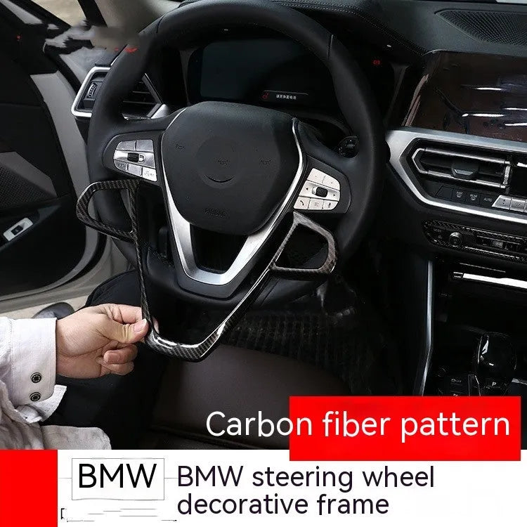 BMW steering wheel button frame decoration in black carbon fibre pattern.