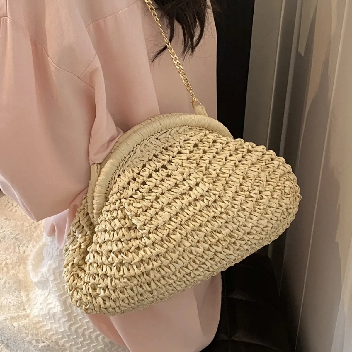 Beige shell-shaped straw shoulder bag with chain strap and woven texture.