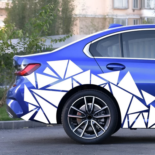 Large roll of coloured vinyl car decal sticker with geometric pattern, shown next to a car rear wheel arch.