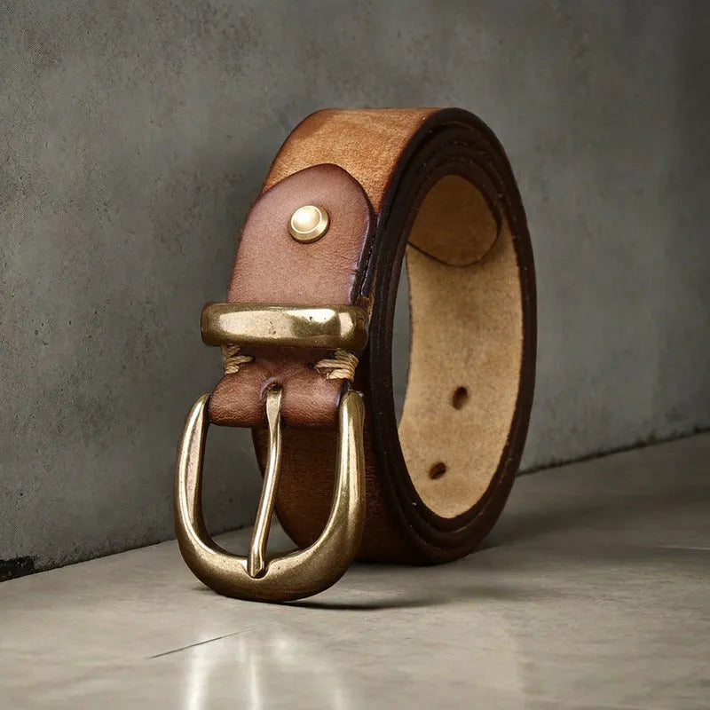 Men's black cattlehide leather belt with a copper pin buckle on a jeans background.