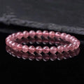 Women's strawberry quartz crystal bracelet with polished beads on a wrist.