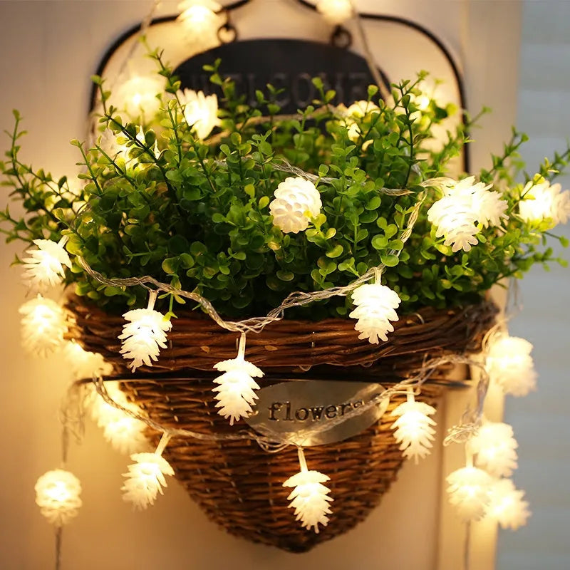 Warm white LED pine cone light string with plastic shells, powered by two AA batteries.