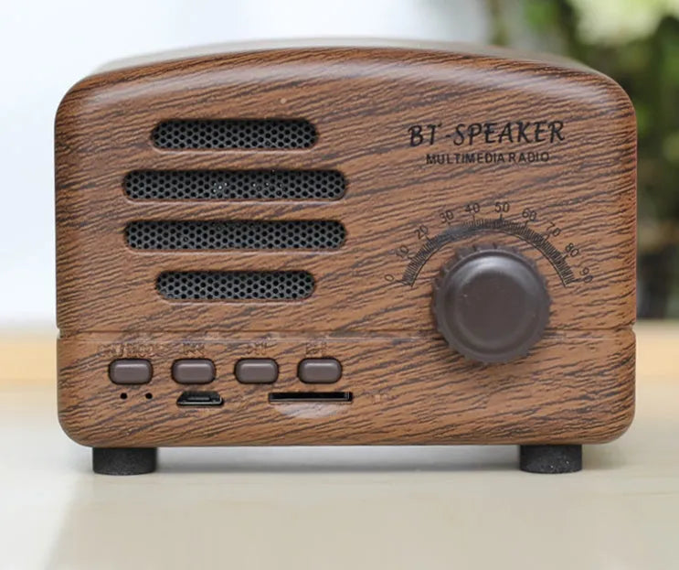 Compact vintage-style wood grain finish Bluetooth speaker on a wooden surface.