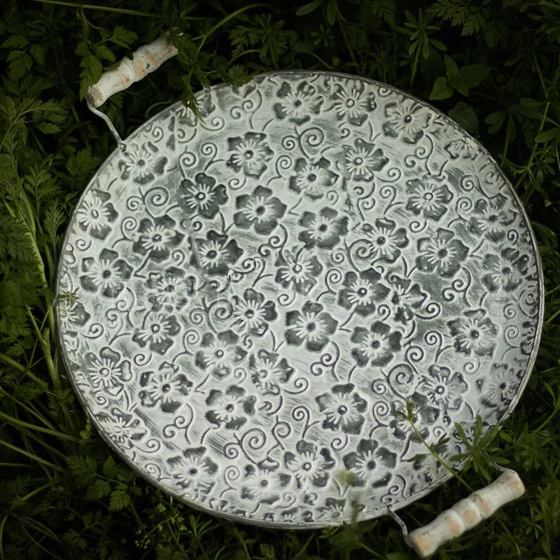 Round wrought iron storage tray in a classic metal colour on a wooden surface.