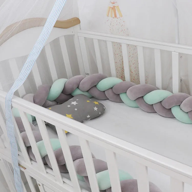 Bendable braid-knot baby crib bumper in spandex velvet, shown in a light grey colour wrapped around a cot.