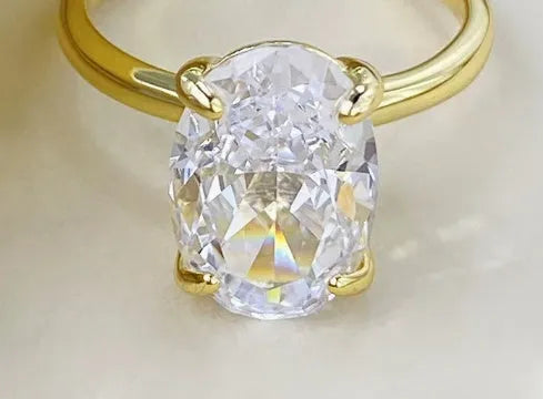 Oval women's ring with four-claw setting holding 6x9mm gemstone in gold or silver finish