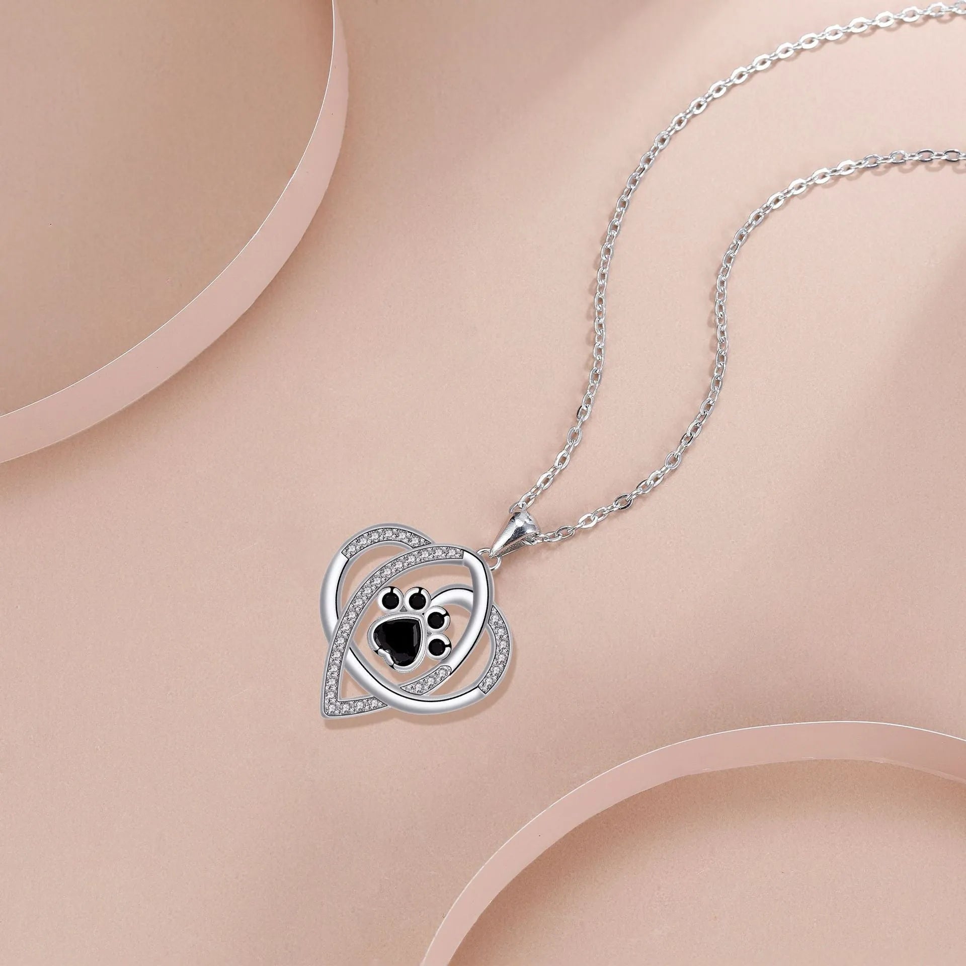 Copper pendant necklace showing a detailed cat and dog paw print design on a cross chain.