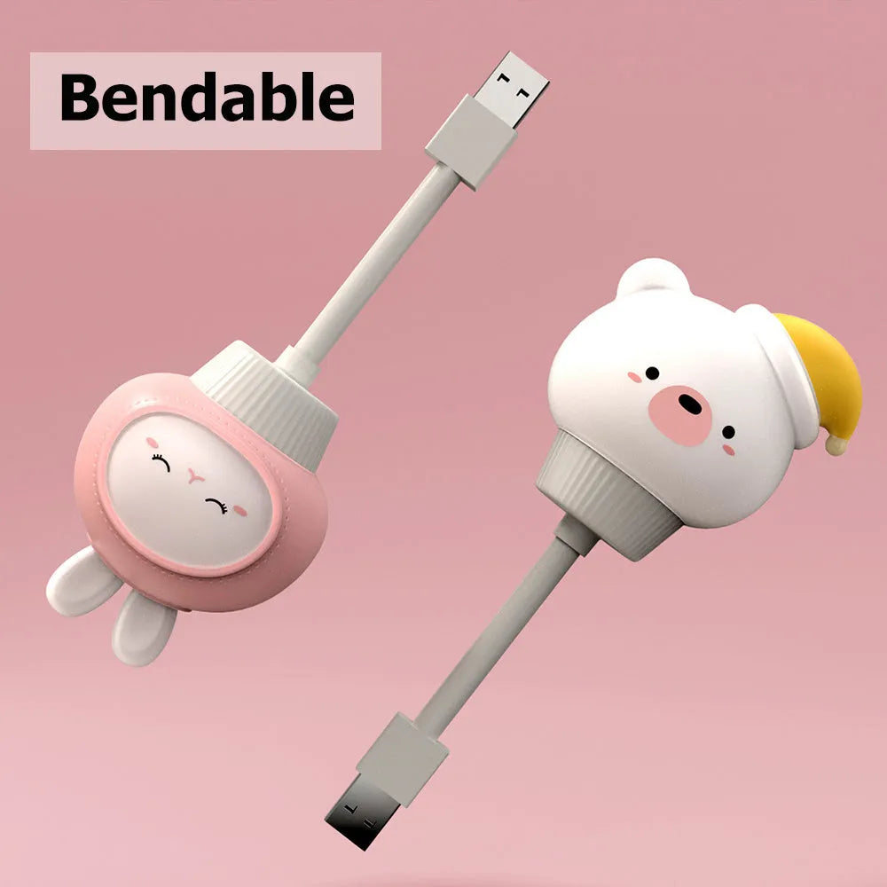 Small cartoon bear-shaped USB night light with remote control on a bedside table.