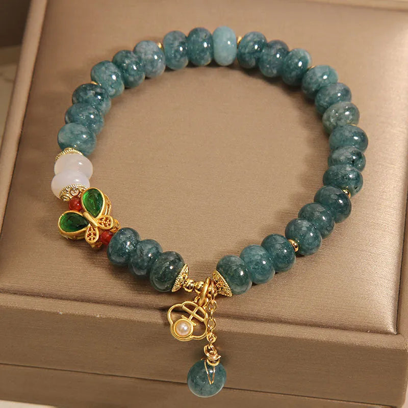 Blue water jade abacus bead bracelet with butterfly charm and white agate on an alloy band.
